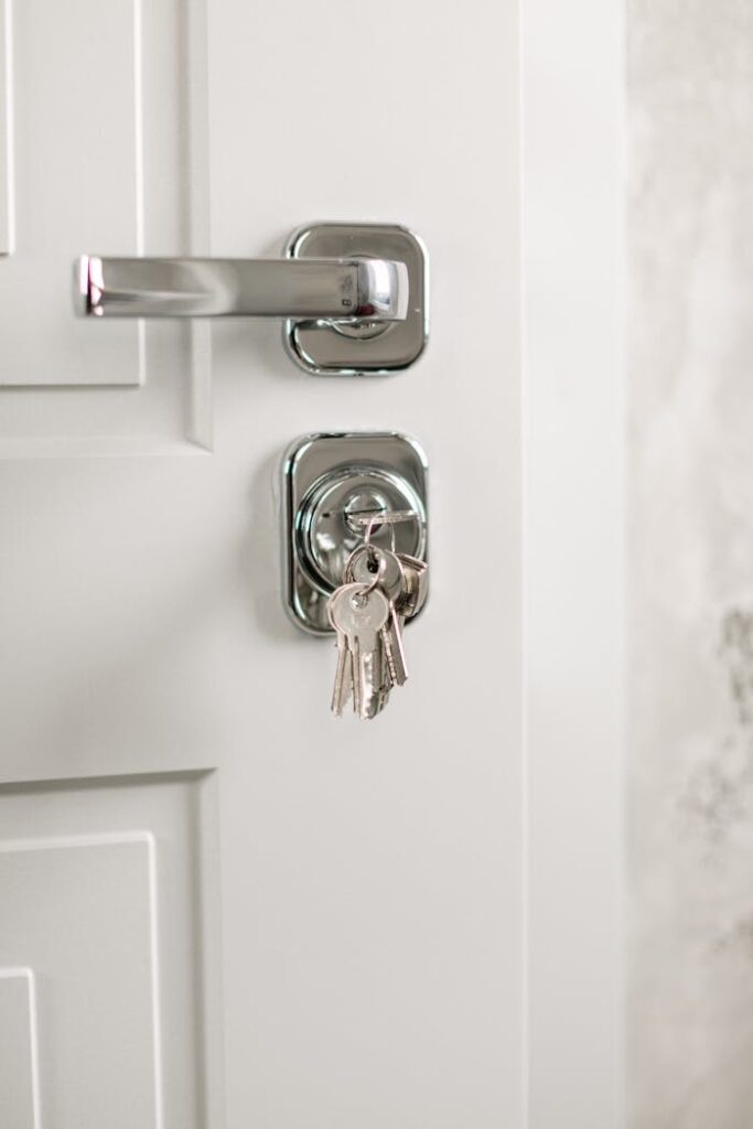 Close-up of a modern silver door handle with keys hanging in the lock, symbolizing security.